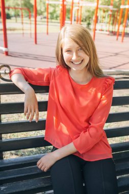 Sırt çantalı güzel bir kız bankta oturuyor.