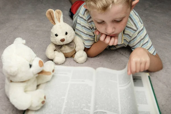かわいい男の子読書本彼のお気に入りのおもちゃ — ストック写真