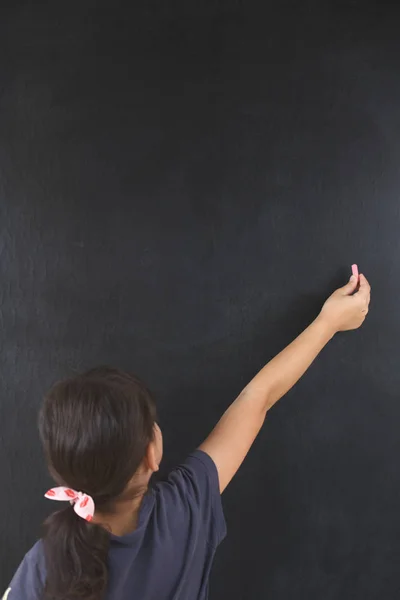 Little girl is writing chalk on a blackboard — Stock Photo, Image