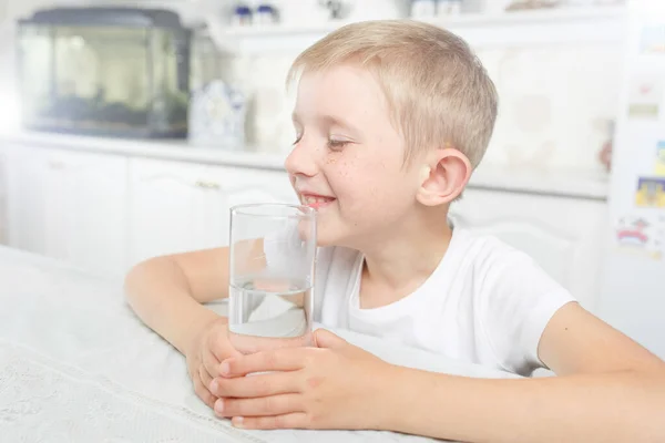 Niño en la cocina con un vaso de agua limpia — Foto de Stock