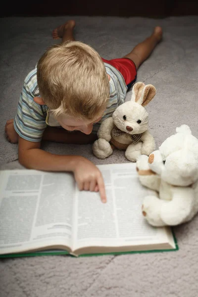 小さな男の子読書本とお気に入りのおもちゃ — ストック写真