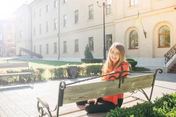 Menina bonita com mochila sentada em um banco — Fotografia de Stock