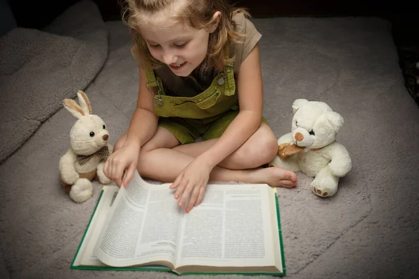 Piękna dziewczynka czytać książki dowcip ulubiona zabawka — Zdjęcie stockowe