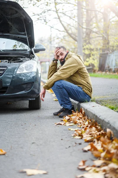 Guy is repairing car on the road