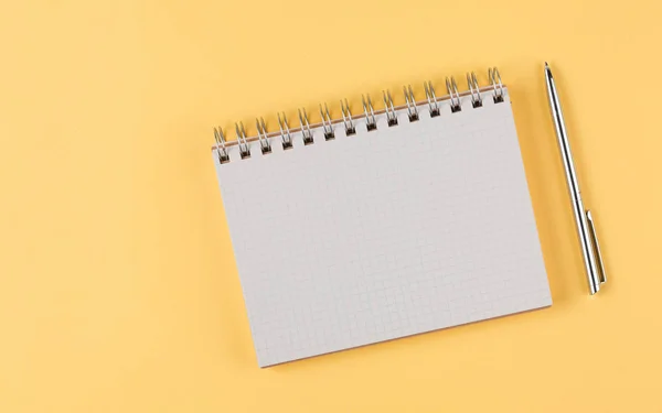 Cuaderno con pluma negra sobre fondo amarillo — Foto de Stock