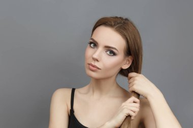 Güzel bir kadın elleriyle saçlarını tutar..