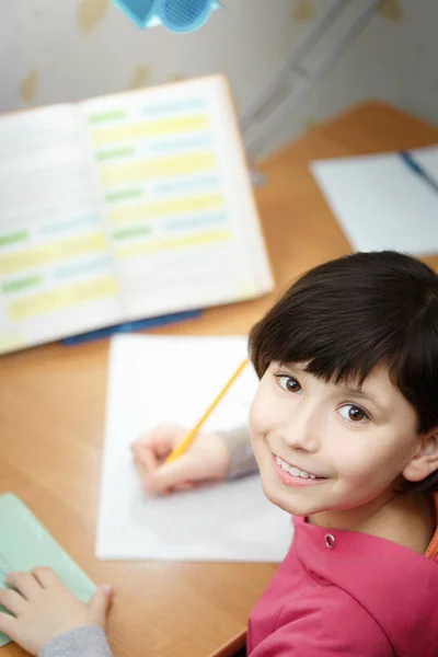 Smiling schoolgirl is doing homework. — Stock Photo, Image