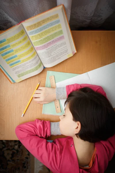 Klein schoolmeisje viel in slaap op school huiswerk. — Stockfoto