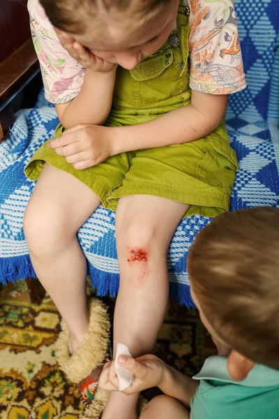 little girl hurt her knee, a boy heals her wound