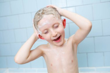 Küçük çocuk duşta yıkanıyor.