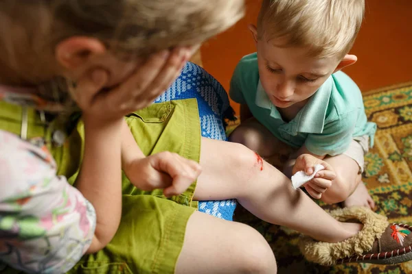 little girl hurt her knee, a boy heals her wound