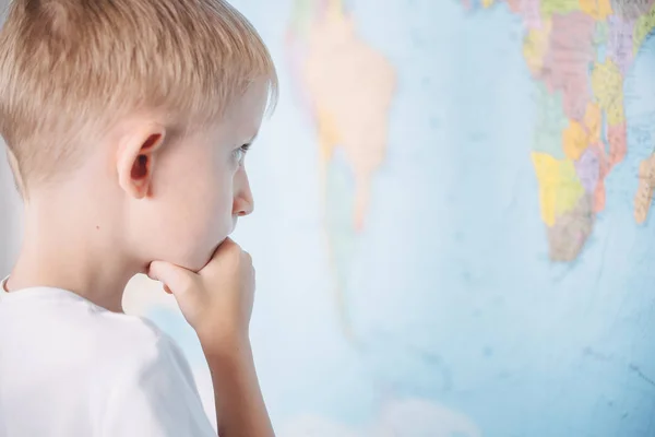 世界地図の背景にいる小さな男の子は — ストック写真