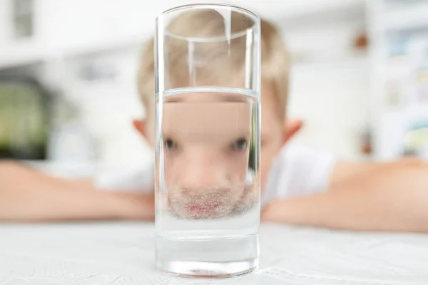 Kleine jongen in keuken met glas schoon water — Stockfoto