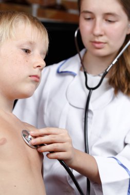 Doktor çocuğun nefesini dinliyor.