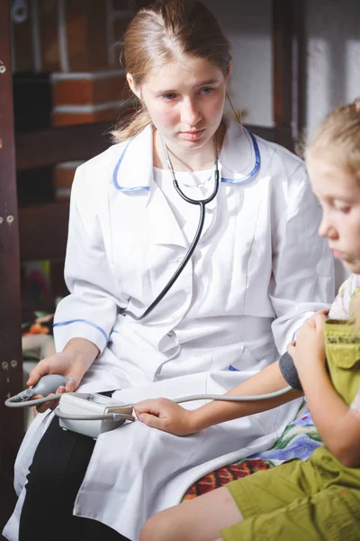 doctor in white coat measures pressure on a child