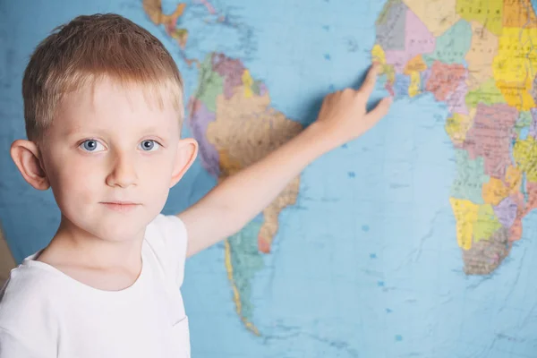 Kleine jongen op de achtergrond van een wereldkaart — Stockfoto