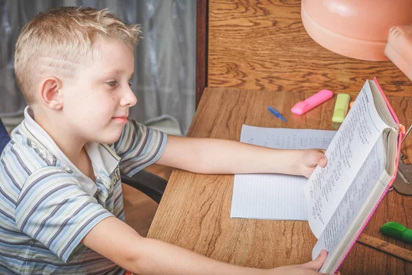 Школьник читает книгу за своим столом — стоковое фото