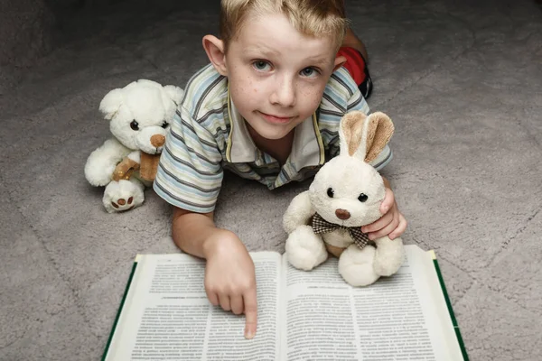 Kleine jongen lezen boek met zijn favoriete speelgoed — Stockfoto