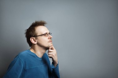Young man with glasses looks at the side