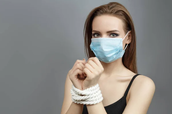 Молодая женщина со связанными руками в медицинской маске — стоковое фото