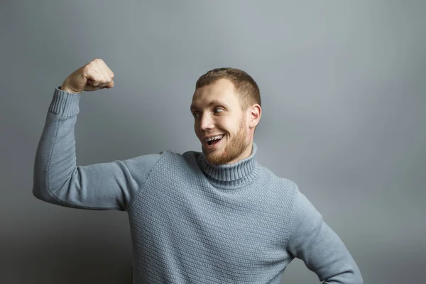 Man in blauwe trui toont biceps — Stockfoto