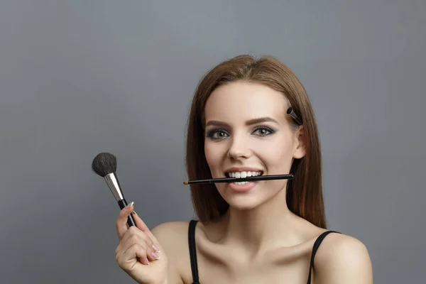 Kvinna med verktyg för make up i händerna — Stockfoto