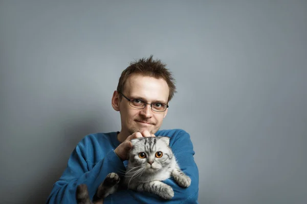 Man with glasses stroking cat holding it in arms