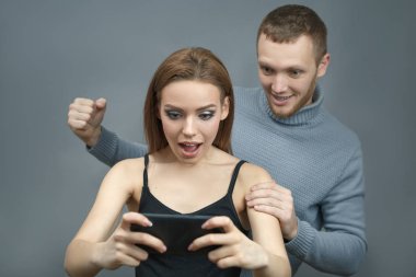 Çift heyecanlı akıllı telefona bakıyor.