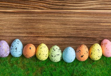 Ahşap arka planda yeşil çimlerde yumurta rengi