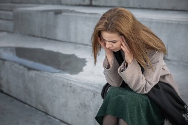 Üzgün, kötü ruh halinde güzel bir kız granit bankta oturuyor..