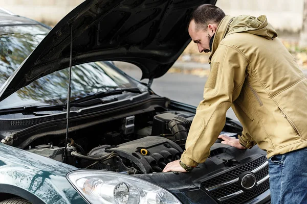 Adam yolda araba tamir ediyor.