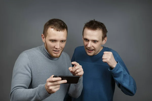 Dois homens com olhar entusiasmado para o smartphone — Fotografia de Stock