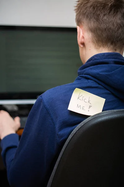 Man at computer with attached note. Kick me. — Stock Photo, Image