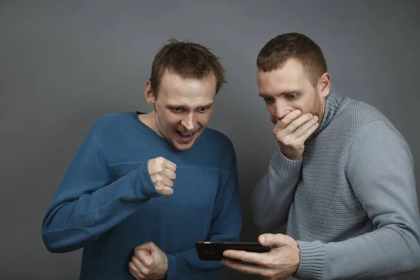 Twee mannen die opgewonden naar de smartphone kijken — Stockfoto