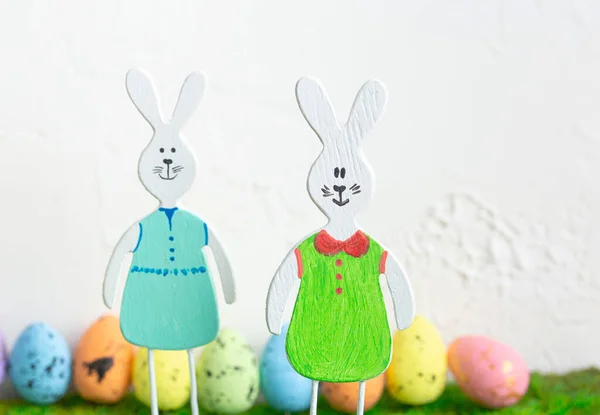 Wooden toy rabbits with colored Easter eggs. — Stock Photo, Image