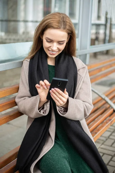 Girl sitting at bus stop and watching in the phone