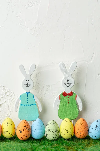 Wooden toy rabbits with colored Easter eggs. — Stock Photo, Image