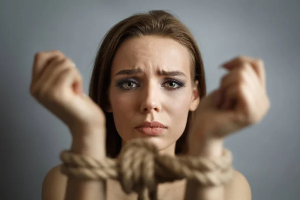 Elleri iple bağlanmış genç bir kadın.