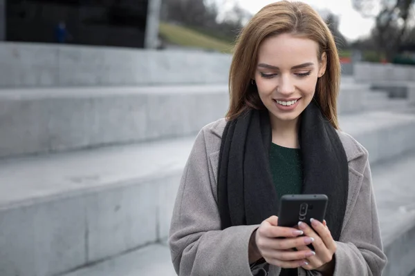 woman stands on the street  watching in smartphone