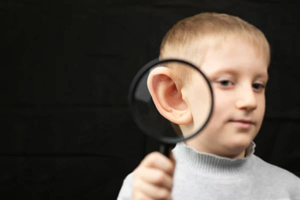 Little boy enlarged his ear with an magnifier. — Stock Photo, Image