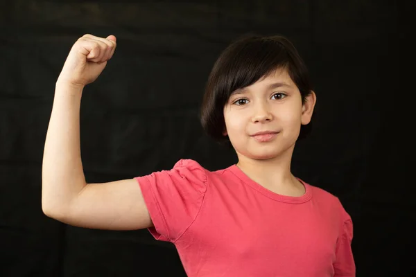 Klein meisje toont haar spieren. — Stockfoto