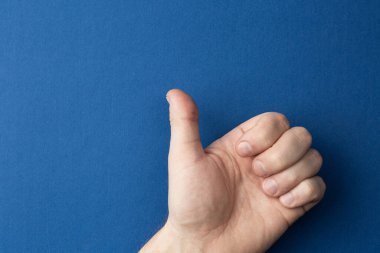 Sol el başparmağını gösteriyor..