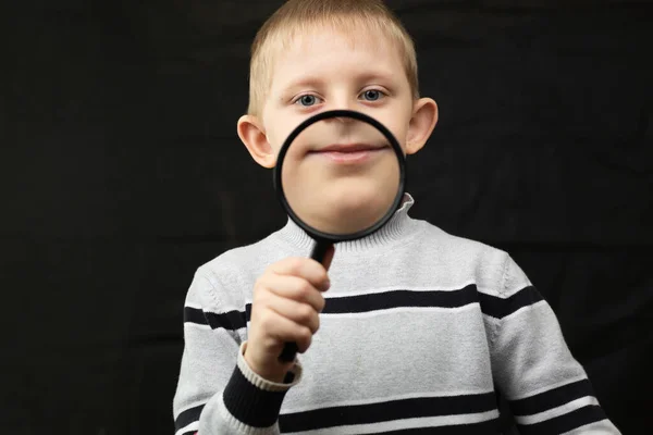 Kleine jongen toont zijn mond met vergroot glas. — Stockfoto