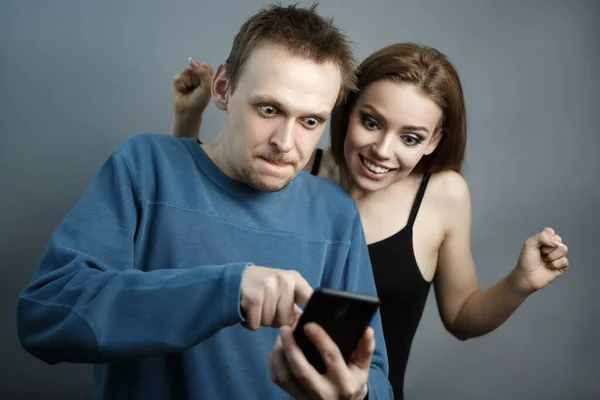 Смешной парень с девушкой, смотрящей на смартфон — стоковое фото