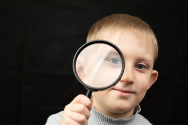 Çocuk büyüteçle bakıyor..