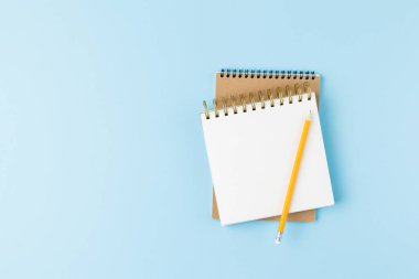 Mavi arkaplanda kalem olan not defteri. 