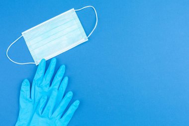 Mavi arka planda tıbbi eldiven ve maske. 