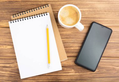 Kalem, akıllı telefon ve kahve fincanlı defter..