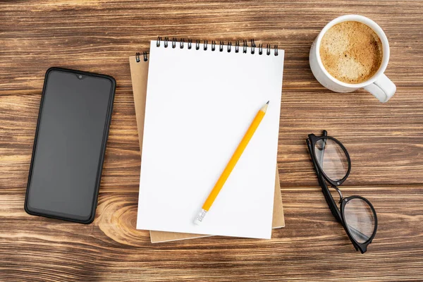Kalemli defter, akıllı telefon, bardak ve kahve..