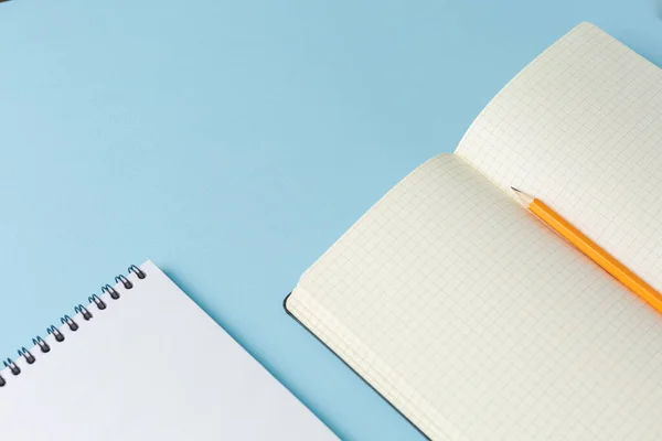 Open notebook with a pencil on blue background.